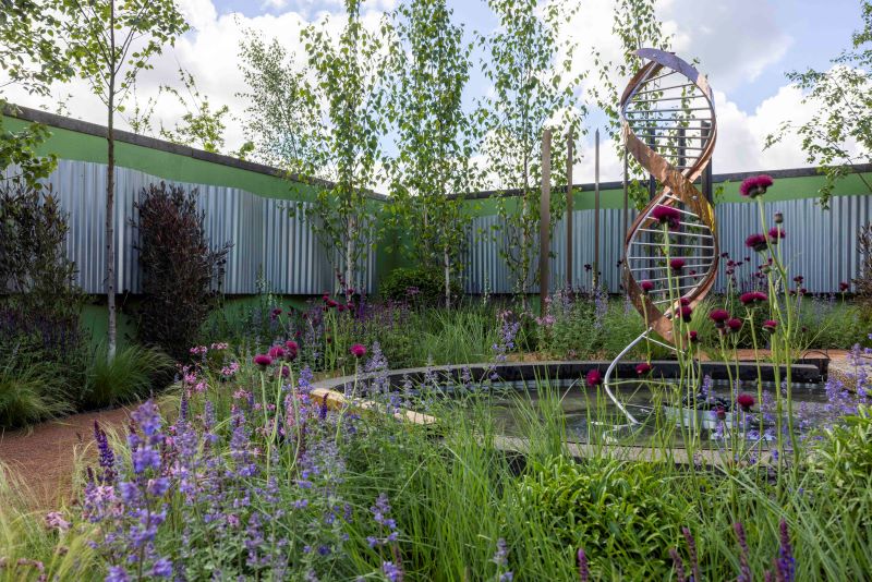 Bord Bia Bloom show garden image, Garden has bright flowers, with a spiral fountain in the middle and bright blue sky,